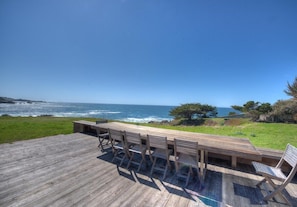 Een houten terras met een tafel en stoelen met uitzicht op de oceaan.