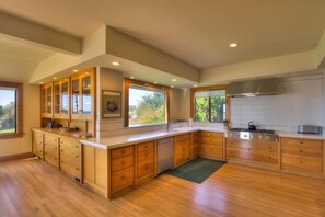 A modern kitchen with wooden cabinets, a built-in dishwasher, and a large window providing natural light.