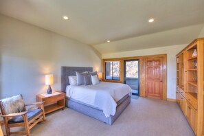 A bedroom with a large bed, a wooden nightstand, a chair, a wardrobe, and a window with a view.