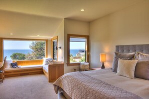 A bedroom with a large bed, a window seat, and a view of the sea. - Sculpture Point - Sea Ranch Whitewater Vista Lodge (Sea Ranch)