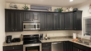 A kitchen with dark cabinets, stainless steel appliances, granite countertops, and decorative wall art.