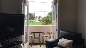 A living room with a TV, a black leather sofa, and a small table.