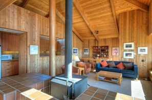 A wooden interior with a fireplace, a sofa, and a dining area. - Kenber House – Don Jacobs Coastal Near Shell Beach (Sea Ranch)
