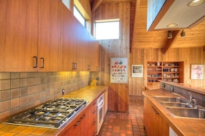 A kitchen with wooden cabinets, a gas stove, and a tiled backsplash.