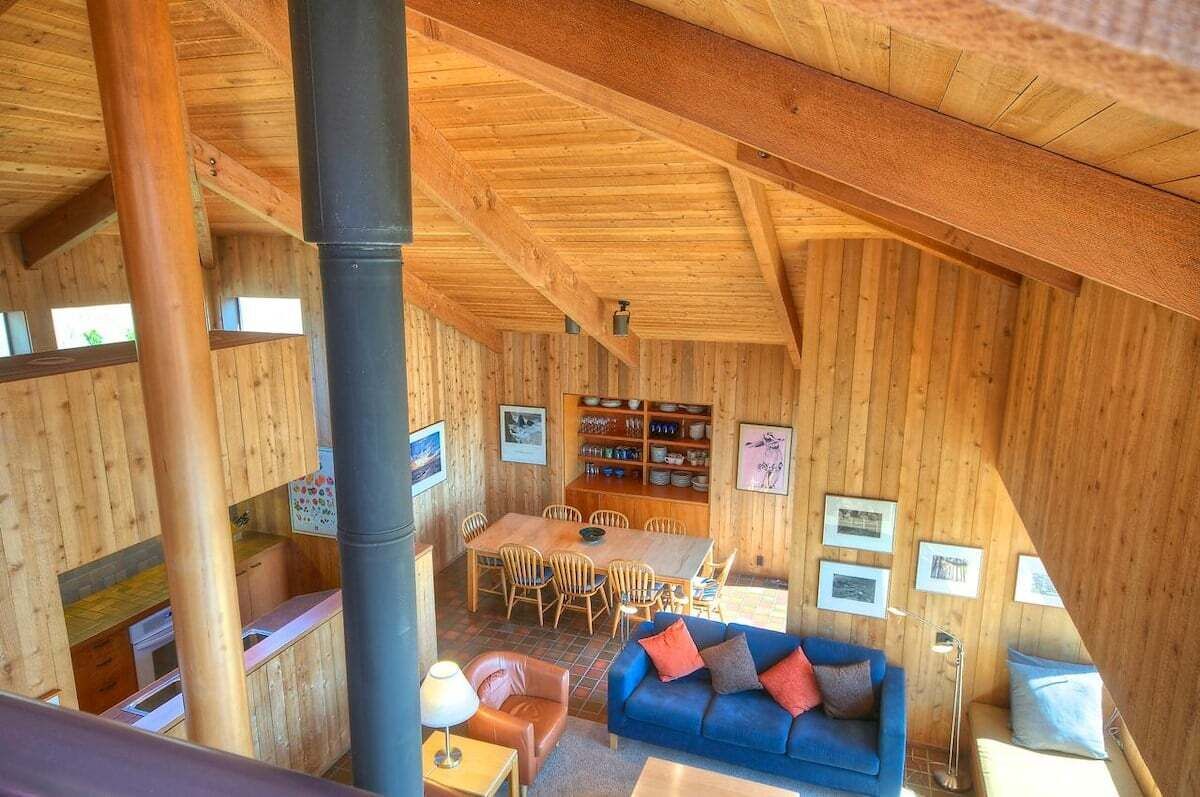 A wooden interior with a dining area, a sofa, and a kitchen.