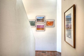 A hallway with four framed artworks on the wall and a large framed picture on the right.