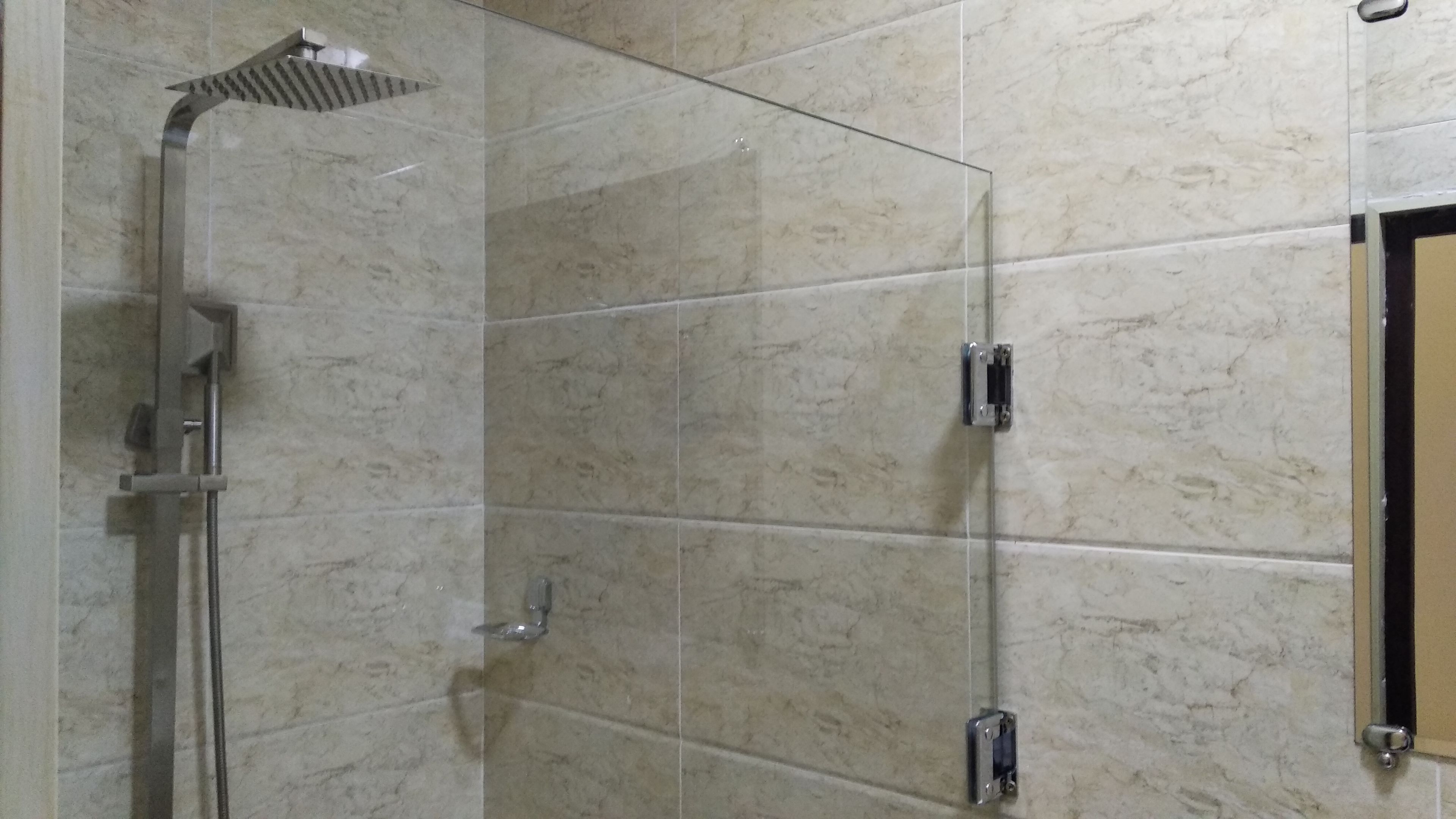 A glass-enclosed shower area with a handheld showerhead and a wall-mounted faucet.