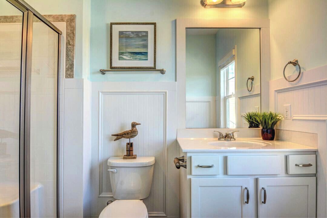 Een badkamer met toilet, wastafel en kastjes.