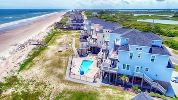 A beachfront property with multiple houses, a swimming pool, and a beach access walkway.