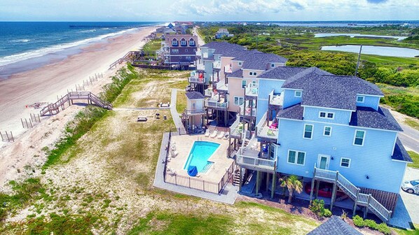 A beachfront property with multiple houses, a swimming pool, and a beach access walkway.