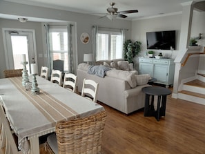 A spacious living area with a dining table, sofa, and a staircase.