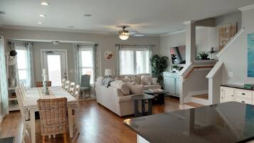 A spacious living area with a dining table, sofa, and kitchen counter.