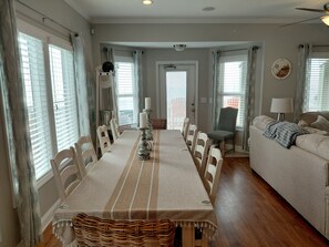 A dining area with a long table, chairs, and a central candle holder. - 3 Little Turtles - Oceanfront, Pool, Hot Tub, Elevator & Backyard. Amazing Views (North Topsail Beach)