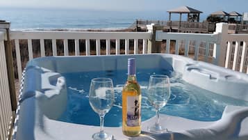 A hot tub with two glasses and a bottle of Duplin Sweet Muscadine wine, overlooking the ocean.