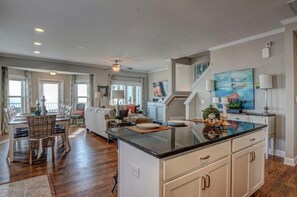 Cozy living area with a central island, dining space, and staircase to an upper level.