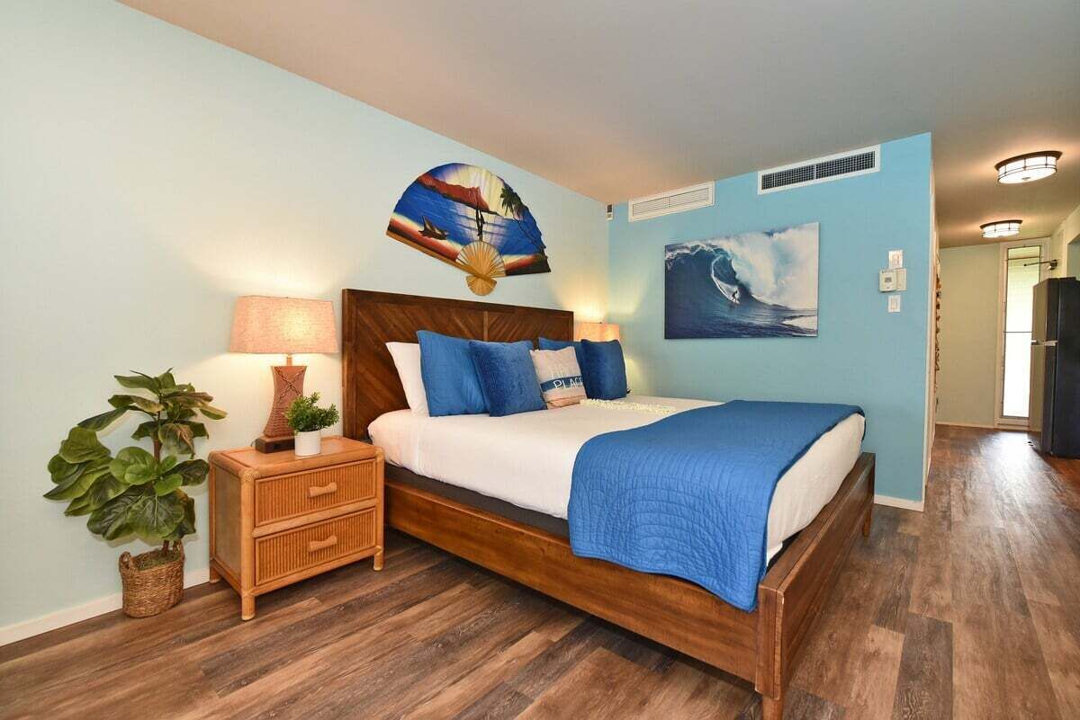 A bedroom with a bed, nightstands, a wall-mounted fan, and a large window.