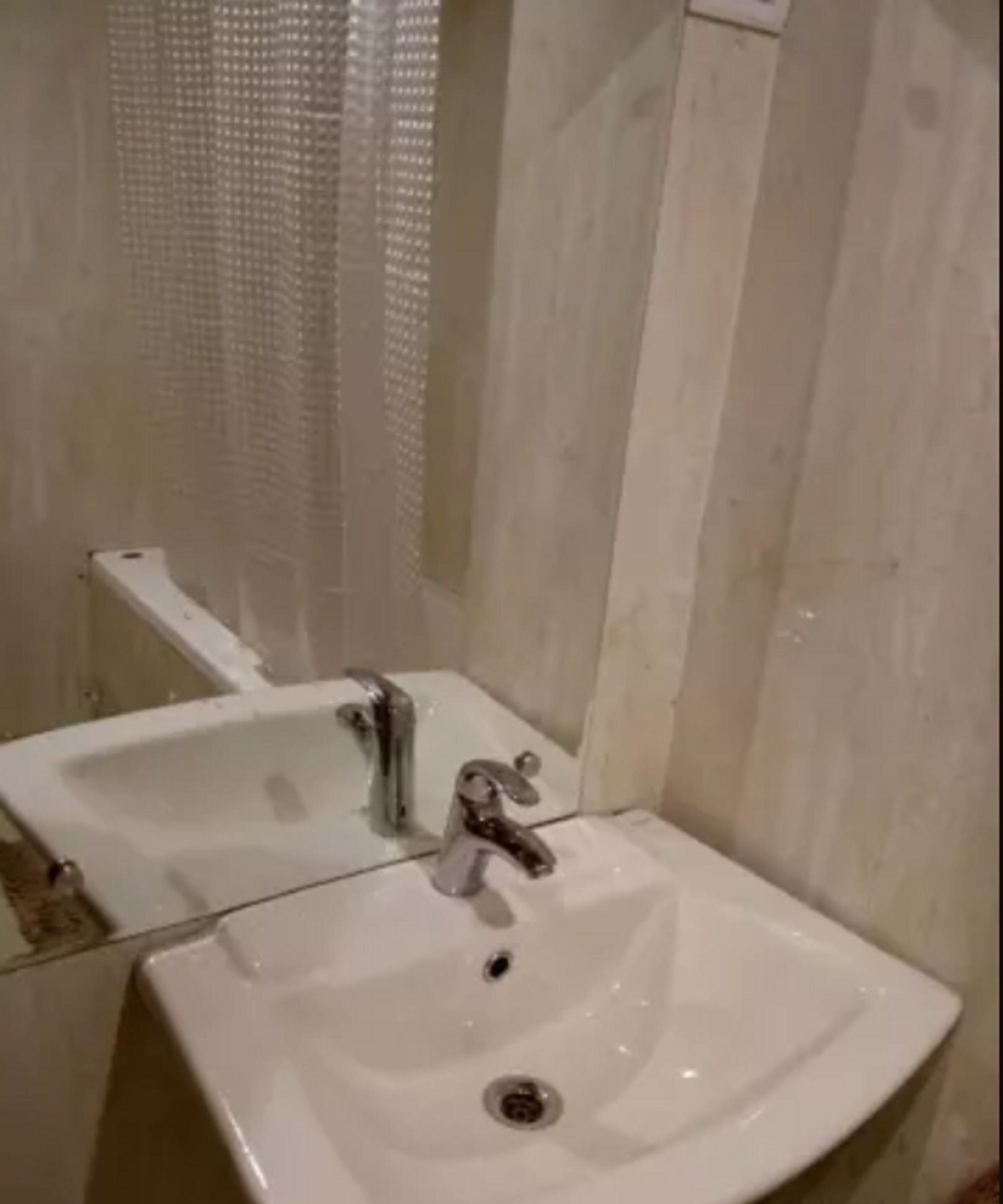 A bathroom with a white sink, a mirror, and a shower curtain.