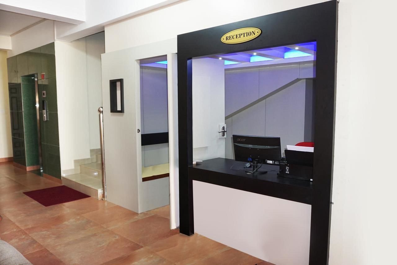 Zona de recepción con mostrador, escalera y ascensor de vidrio.