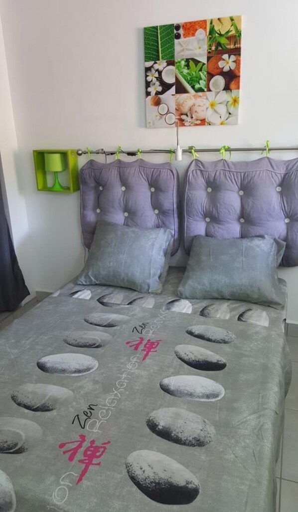A bed with a grey blanket featuring rock patterns and Chinese characters, flanked by two pillows.