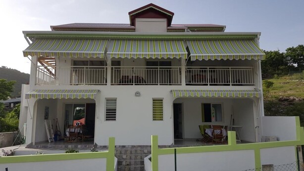 A two-story building with a balcony and a garage. - SUBLIME F2 ANY COMFORT (Les Saintes)