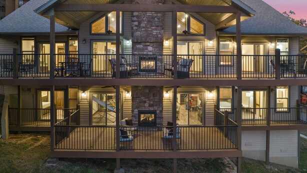 A two-story building with a stone fireplace, balconies with railings, and multiple windows. - Luxe Lodge: Gaming Paradise W/ Breathtaking Lake Views, Indoor Pool Close to SDC (Branson)