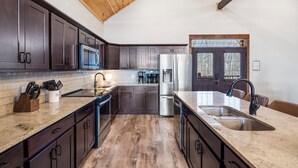 A modern kitchen with dark wood cabinets, stainless steel appliances, and a wooden ceiling. - Luxe Lodge: Gaming Paradise W/ Breathtaking Lake Views, Indoor Pool Close to SDC (Branson)