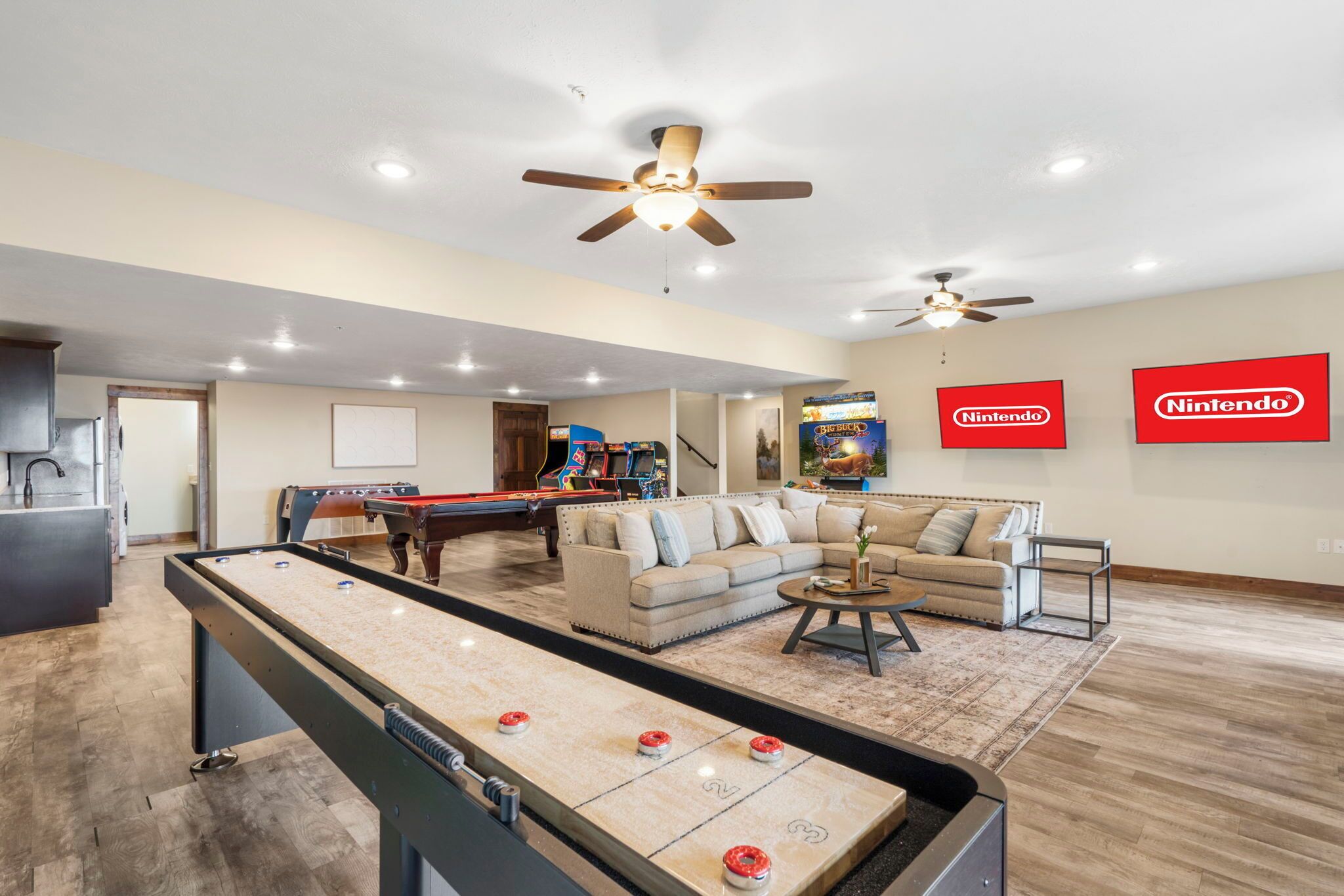 A spacious living area with a pool table, sofas, and a Nintendo gaming setup.