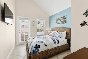 Un dormitorio con cama, televisión, ventana y decoración en la pared.