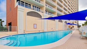 A swimming pool with a curved edge, surrounded by a tiled deck and lounge chairs. - San Carlos 1009 | Beautiful, oversized, beach front, walk to Gulf Shores favorites! (Gulf Shores)