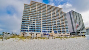 A large hotel with multiple floors and balconies, situated on a sandy beach with a clear sky. - San Carlos 1009 | Beautiful, oversized, beach front, walk to Gulf Shores favorites! (Gulf Shores)