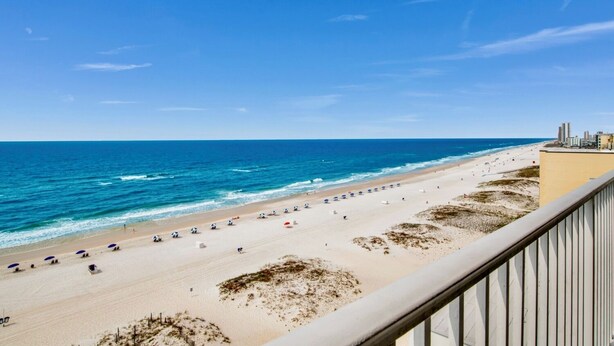 A beach view from a balcony with a clear sky, sandy beach, and ocean. - San Carlos 1009 | Beautiful, oversized, beach front, walk to Gulf Shores favorites! (Gulf Shores)