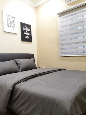 A bedroom with a bed, two wall art pieces, and a window with blinds. - DeKota Homestay Jonker Melaka (Malacca City)
