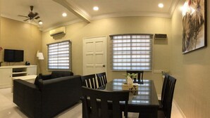 A living room with a sofa, a dining table with chairs, a ceiling fan, and a TV on a stand. - DeKota Homestay Jonker Melaka (Malacca City)