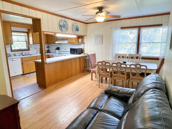 A compact kitchen with wooden cabinets, a microwave, and a dining area with a table and chairs.