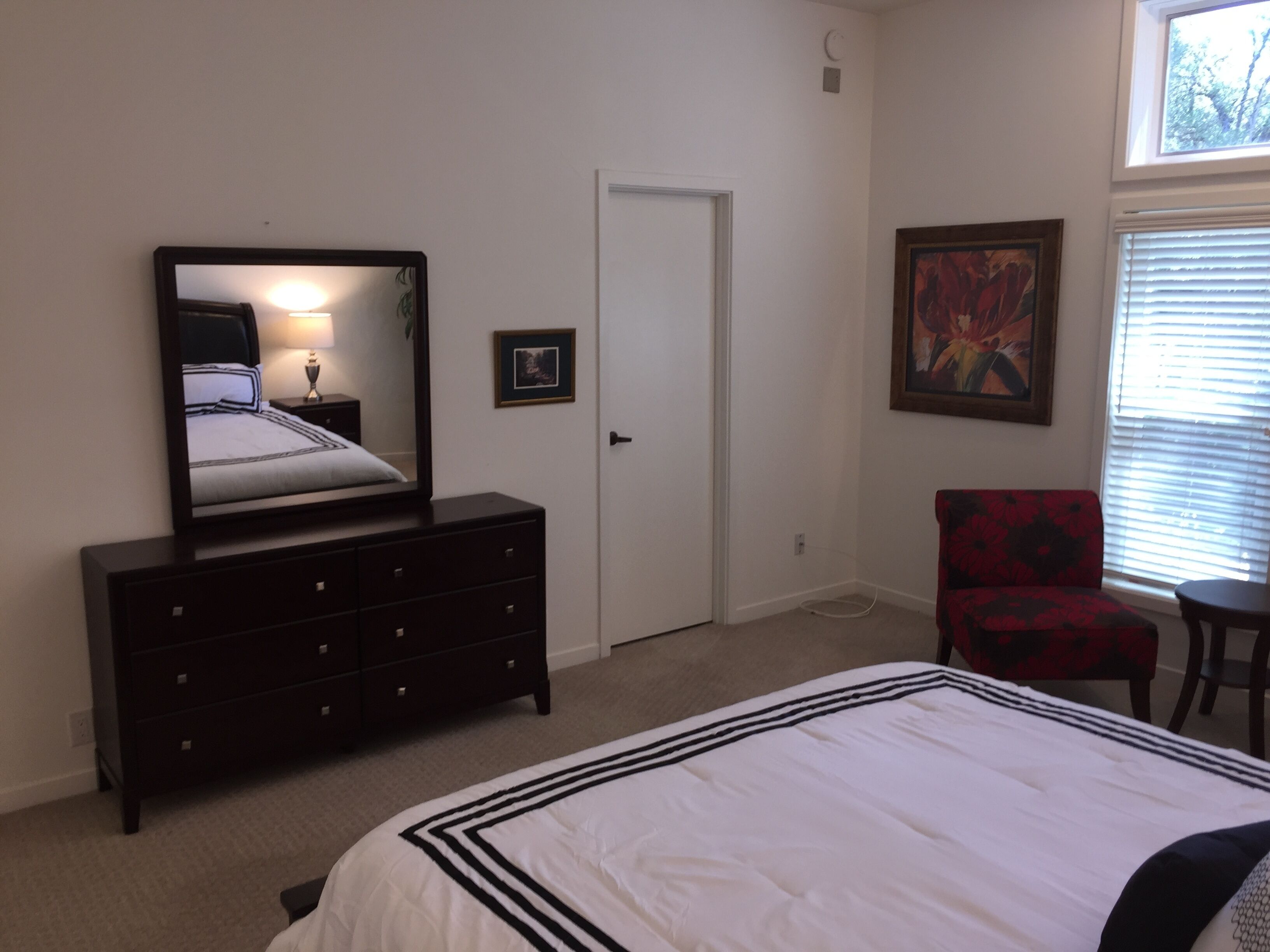 Quarto com cama, cômoda, cadeira e um quadro na parede.