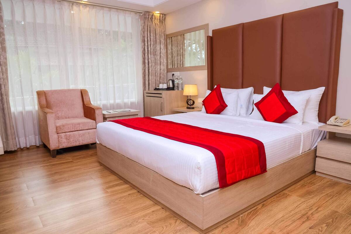 Una habitación de hotel con una cama grande, una silla, un escritorio y una mesita de noche.