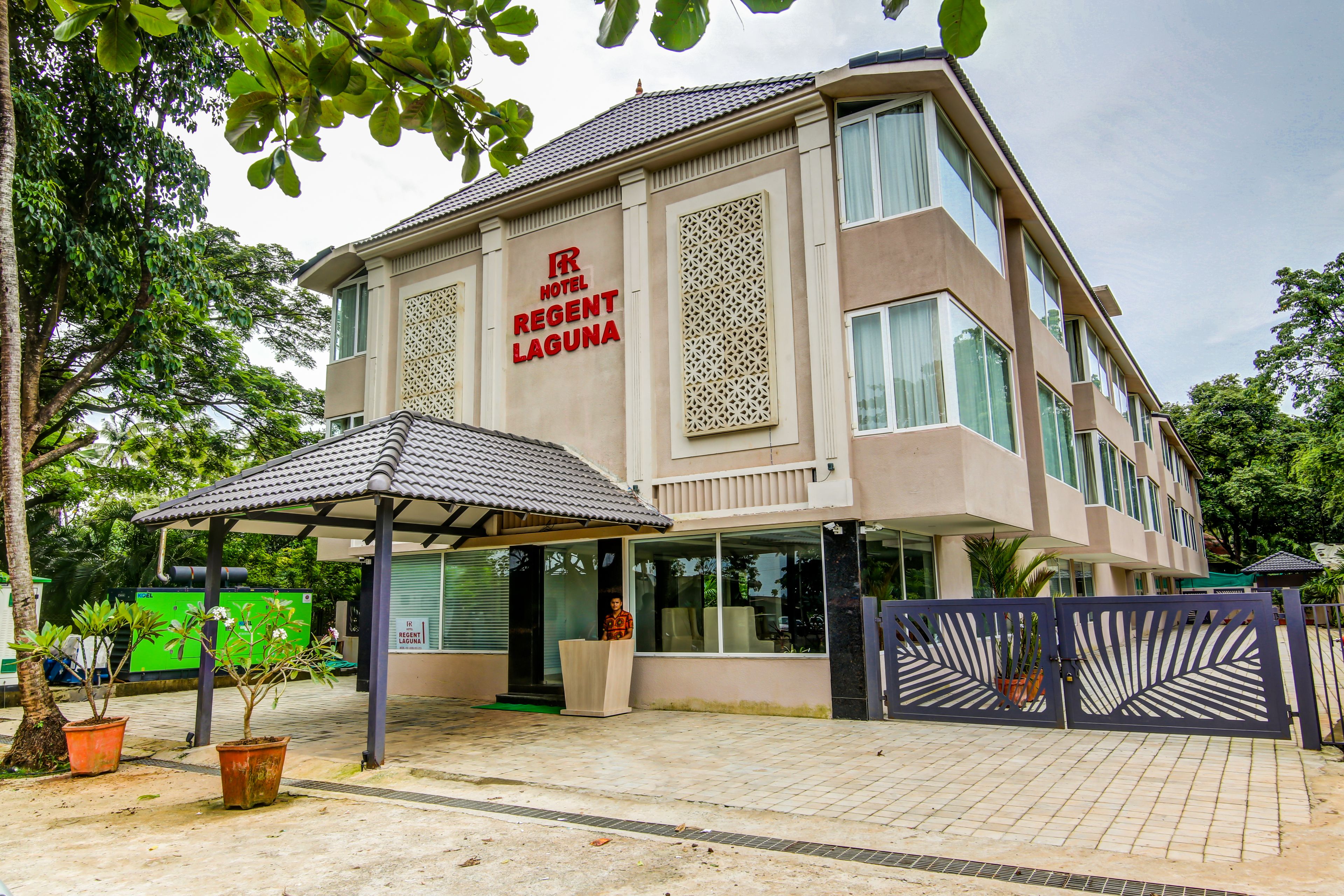 A hotel with a modern facade, a covered entrance, and a gated driveway.
