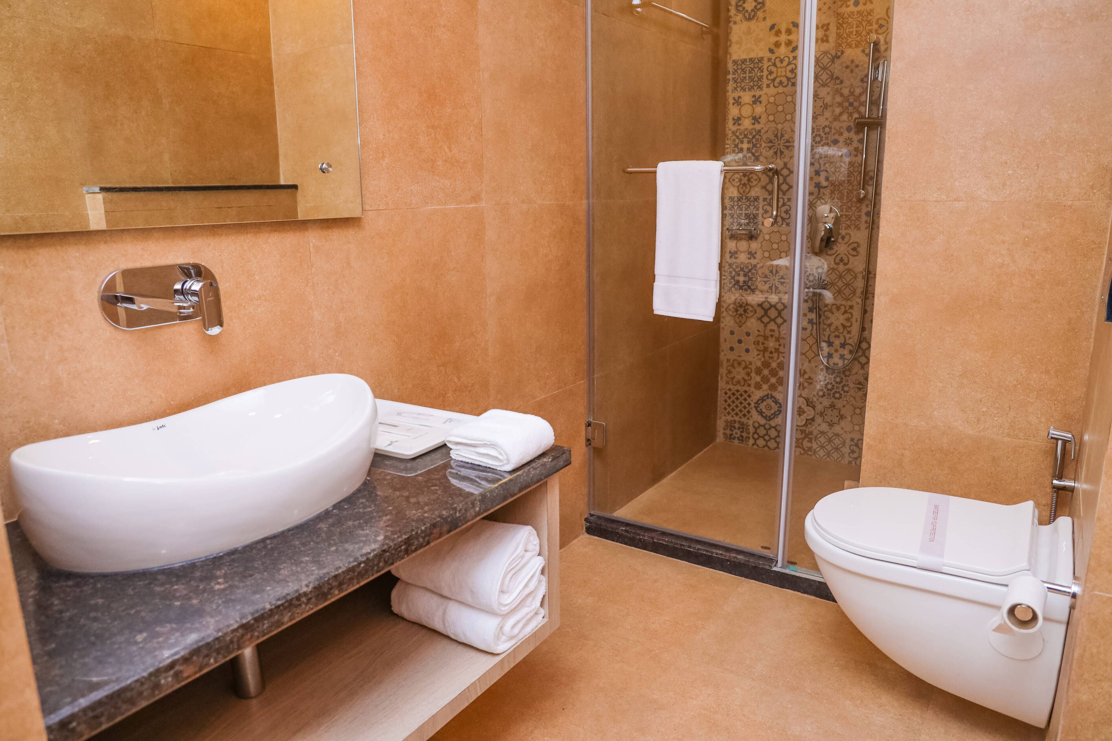 Ein modernes Badezimmer mit einem großen, weißen Waschbecken, einer Duschkabine aus Glas und einer Toilette.