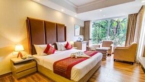 Habitación de hotel con una cama grande, un escritorio, una silla y vistas al exterior.