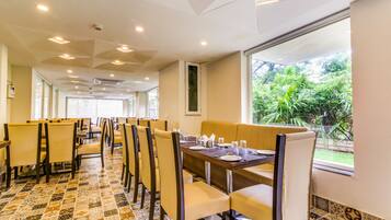 Um restaurante com um espaço amplo de refeições, várias mesas e cadeiras.