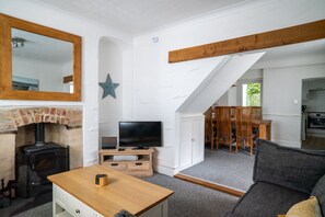 Una sala de estar con chimenea, televisor, mesa de madera y sofá.