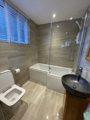 Une salle de bain moderne équipée de toilettes, d’un bidet, d’une baignoire et d’un lavabo sur pied.