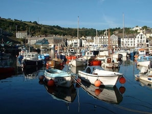 A harbor with boats docked, calm water, and buildings in the background.