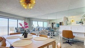 Ein modernes Wohnzimmer mit Essbereich, großen Fenstern und Meerblick.