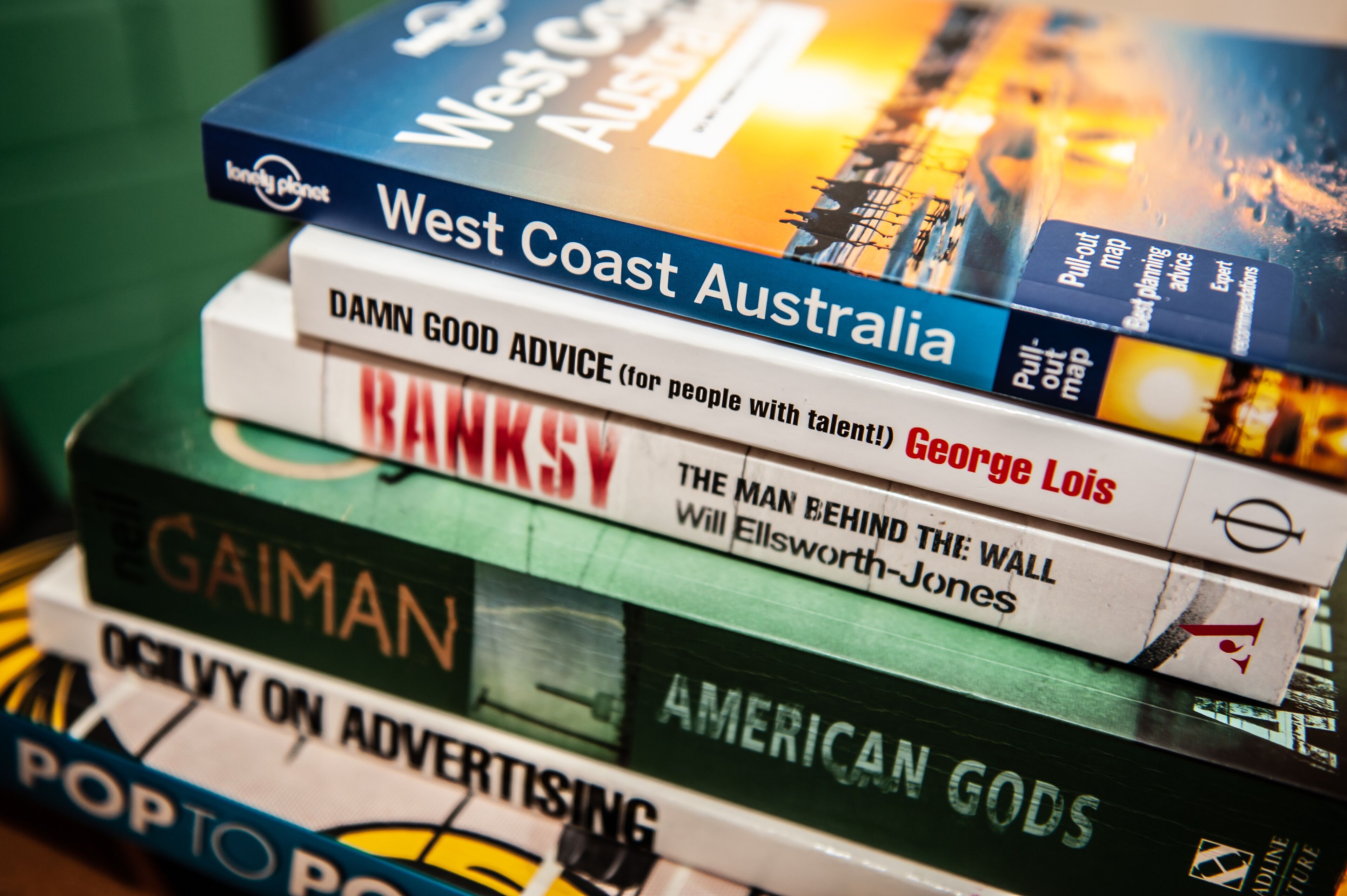 A stack of books with titles including 'West Coast Australia' and 'Damn Good Advice'.