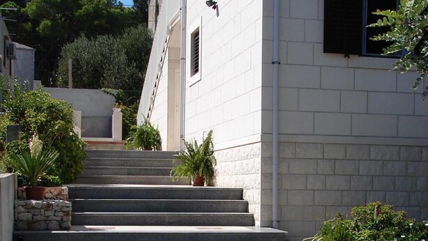 A set of concrete steps leading up to a white building with a red car parked nearby. - Apartments Magda - Two Bedroom Apartment with Terrace and Garden View (Supetar)