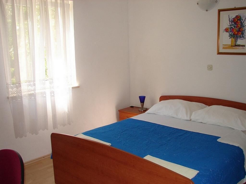 A bedroom with a bed, a nightstand, a lamp, and a window with curtains.