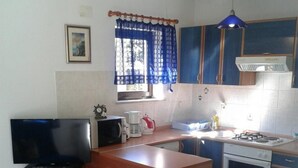 A compact kitchen with a TV, microwave, coffee maker, and stove. - Apartments Magda - Two Bedroom Apartment with Terrace and Garden View (Supetar)