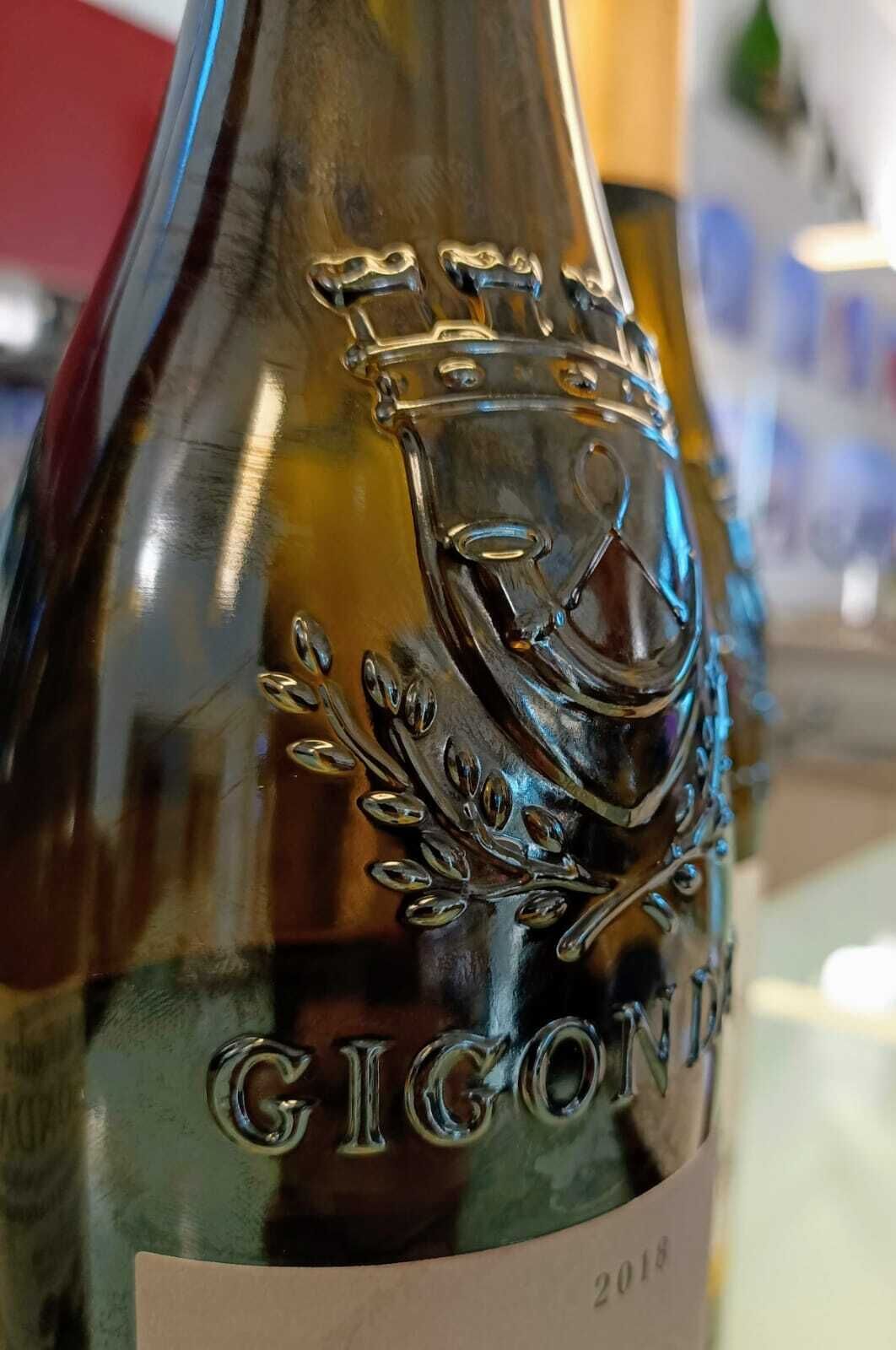 Primer plano de una botella de vino con texto en relieve y un emblema de corona, lo que indica un producto de alta calidad.