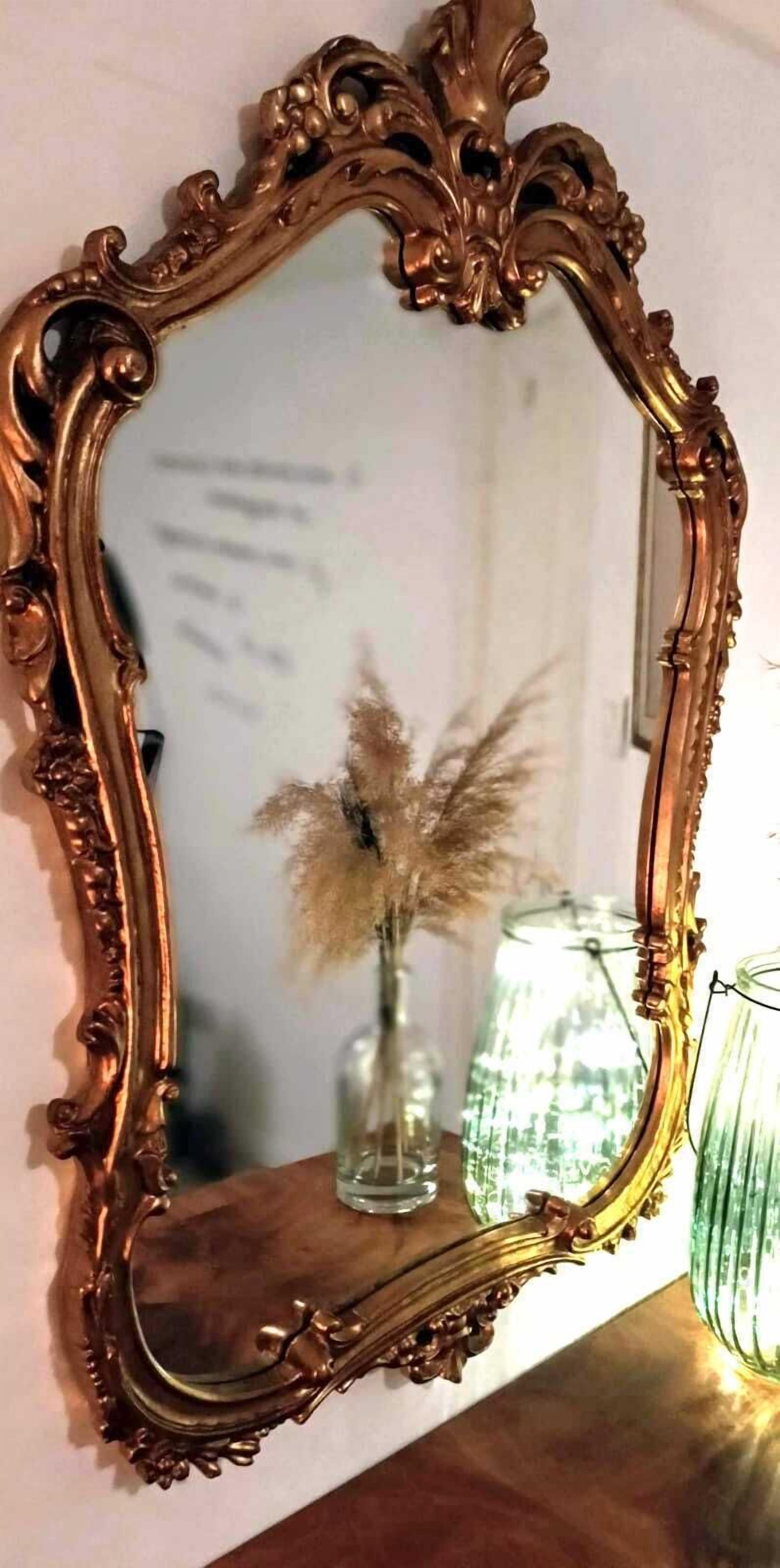Un espejo con un marco dorado ornamentado.